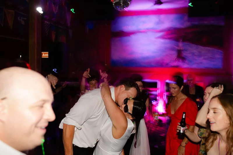 A bride and groom dancing and embracing at their wedding in Sausalito, California, while sporting white face painting from the glitter bar
