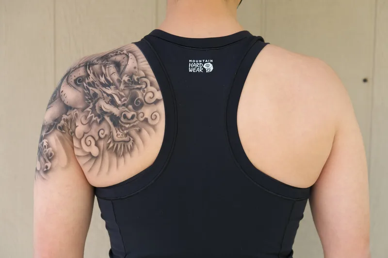 A young light skinned person modeling a realistic dragon airbrush tattoo on their shoulder in Palo Alto, California