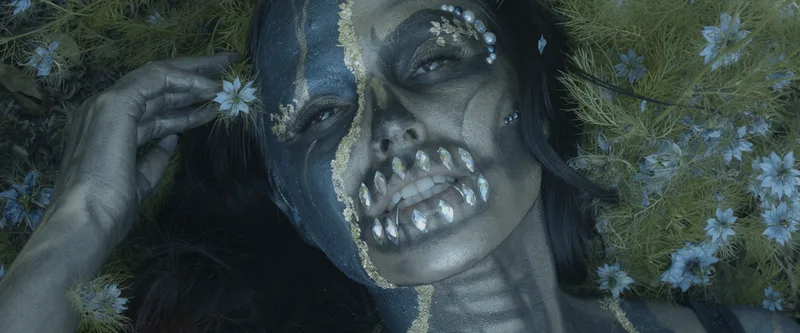 A young woman wears blue and gold skull face and body painting with diamond teeth, San Francisco